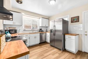 a kitchen with white cabinets and a stainless steel refrigerator at Cozy Ranch Home a Walk from St John's Hospital! in Detroit