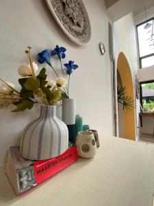 a white vase with flowers sitting on top of a book at Living Sage Chiang Mai - Boutique Art House in Chiang Mai