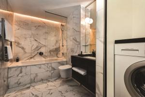 a bathroom with a tub and a toilet and a sink at Adina Apartment Hotel Frankfurt Westend in Frankfurt/Main