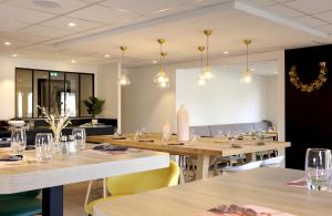 a restaurant with wooden tables and yellow chairs and lights at Campanile NATURE - Limoges Nord in Limoges