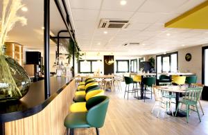 a restaurant with green and yellow chairs and tables at Campanile Limoges Nord in Limoges