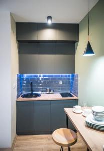 uma cozinha com azulejos azuis, um lavatório e uma mesa em BEST APARTMENTS em Bitola