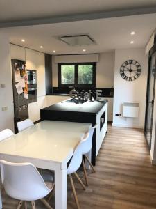 eine Küche mit einem Tisch, weißen Stühlen und einer Uhr in der Unterkunft Casa en Sant Cugat in Sant Cugat del Vallès