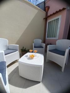 un grupo de sillas y mesas blancas de mimbre en un patio en La vie en rose, en Mola di Bari