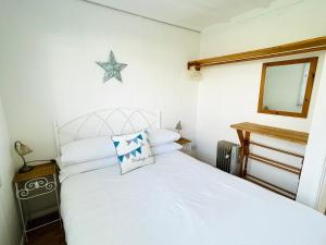 a bedroom with a white bed with a star on the wall at Lucy Lou, charming holiday bungalow in Devon in Galmpton-on-the-Dart