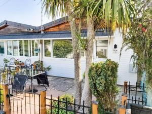 a white house with a palm tree and a patio at Lucy Lou, charming holiday bungalow in Devon in Galmpton-on-the-Dart