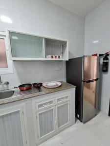 uma cozinha com armários brancos e um frigorífico de aço inoxidável em هومينج - Homing (شقق مفروشة) em Salalah