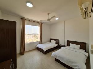 a bedroom with two beds and a window at هومينج - Homing (شقق مفروشة) in Salalah