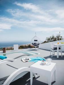 a white table and chairs next to a swimming pool at Anthemis Suites in Imerovigli