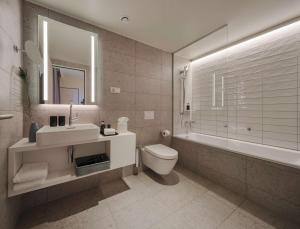 a bathroom with a sink and a toilet and a tub at Adina Apartment Hotel Cologne in Cologne