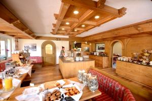 a restaurant with tables and a man in the kitchen at Naturhotel Café Waldesruhe in Oberstdorf