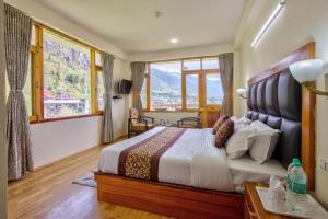 a bedroom with a large bed with a large window at Thrill Nature Cottage in Manāli