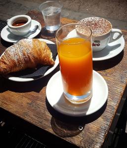 una mesa con un vaso de zumo de naranja y un cruasán y una taza en B&B La margherita en Castellammare di Stabia