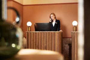 a woman standing at a podium talking on a phone at Adina Apartment Hotel Stuttgart in Stuttgart