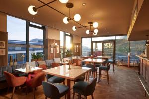 ein Restaurant mit Tischen und Stühlen und großen Fenstern in der Unterkunft Adina Apartment Hotel Stuttgart in Stuttgart