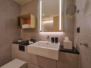 een badkamer met een witte wastafel en een spiegel bij Adina Apartment Hotel Stuttgart in Stuttgart