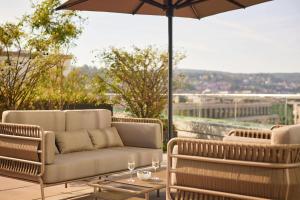 a patio with a couch and a table with an umbrella at Adina Apartment Hotel Stuttgart in Stuttgart