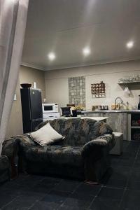 a living room with a couch in front of a kitchen at Rensch Place in Bloemfontein