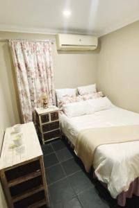 a small bedroom with two beds and a table at Rensch Place in Bloemfontein