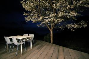 a table and chairs on a deck with a tree at 1日1組限定貸切宿 Kitohana YUYA in Nagato