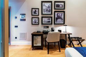 Habitación con escritorio con silla y cuadros en la pared. en Boutique Hotel Cordial Plaza Mayor de Santa Ana en Las Palmas de Gran Canaria