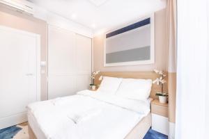 a bedroom with a white bed and a window at VacationClub - Boulevard Residence Apartament 21 in Ustronie Morskie