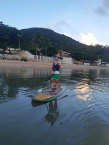 a woman is standing on a paddle board in the water at Por do Sol in Florianópolis