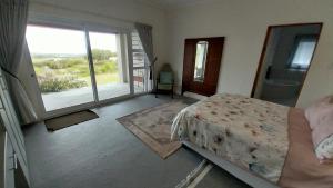 a bedroom with a bed and a large window at Blombos Self-Catering House in Franskraal