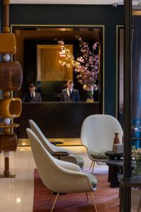 パリにあるホテル モンタレンバールの鏡の前に椅子を置いたサロンの男性二人