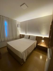 een slaapkamer met een wit bed en een raam bij Hotel Linhatur in Linhares