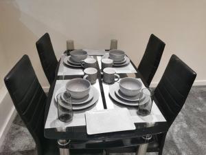einen schwarzen Tisch mit schwarzen Stühlen und einen Tisch mit Tellern und Geschirr in der Unterkunft Paramount city view in Swindon