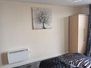 ein Schlafzimmer mit einem Bett und einem Bild eines Baumes in der Unterkunft Paramount city view in Swindon