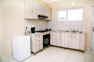 a kitchen with wooden cabinets and a sink and a refrigerator at AS Guesthouse & Self-catering in Swakopmund