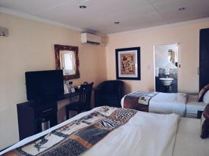 a hotel room with two beds and a television at Ecotel Premier Lodge & Conference Centre in Benoni