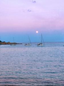 three boats sitting in the water at sunset at porto frailis Arbatax casa vista mare in Àrbatax