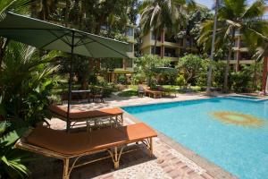 a pool with chairs and an umbrella next to a building at Palolem Luxury Apartments in Canacona