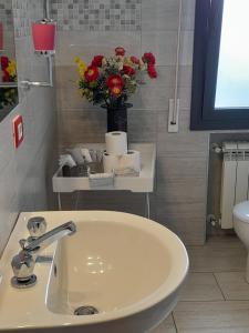 a bathroom with a sink and a vase of flowers at Appartamento ORNELLO in Pietrasanta