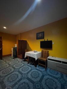 Cette chambre dispose d'une table, d'une télévision et de murs jaunes. dans l'établissement 95 restaurant, à Nai Thon Beach