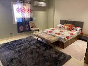 a bedroom with a bed and a chair and a rug at Luxury apartment in front of the AUC in Cairo
