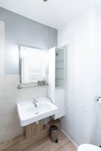 uma casa de banho branca com um lavatório e um espelho em L'unique em Saint-Étienne