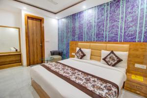 1 dormitorio con cama grande y pared morada en FabHotel Gross Inn Suites en Nueva Delhi
