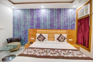 a bedroom with a bed and a purple wall at FabHotel Gross Inn Suites in New Delhi