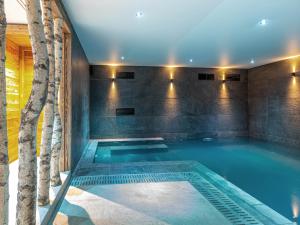 a swimming pool in a house with a tree at Chalet de luxe avec piscine, sauna, hammam, cinéma et salle de jeu - FR-1-694-3 in Val dʼIsère