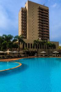 a large swimming pool in front of a tall building at Marques Plaza Hotel in Pouso Alegre