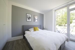 um quarto branco com uma cama grande e uma janela em VARIAS Lifestyle Apartments em Elsau