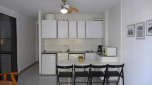 una cocina con armarios blancos y una mesa con sillas. en Apartamentos Amatista, en Salou