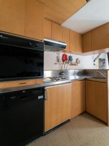 una cocina con electrodomésticos negros y armarios de madera en Mandron charming and central apartment en Madonna di Campiglio