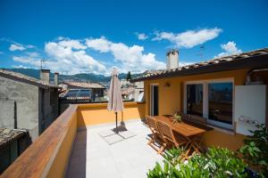 a balcony with an umbrella and a wooden table at Mala Silex Apartments in Malcesine