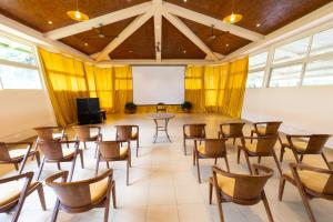 una sala de conferencias con mesas, sillas y una pantalla en Honeydewwz Exoticaa Hotel & Resort, en Chikmagalur