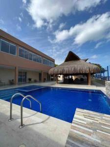 a swimming pool with a straw umbrella and a building at Dianamar house, Te mereces disfrutarlo in Ríohacha